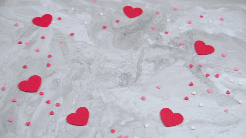 Many red heart shaped confetti falling on the table.