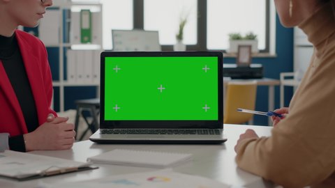 Close up of colleagues using green screen on laptop to work on business in office. Coworkers using mock up template and isolated chroma key on blank background. People working with mockup.