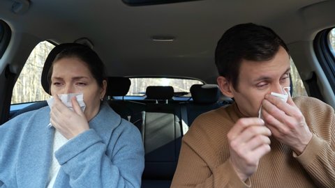 Married couple man and woman catches cold during trip and continues sneezing and blows noses all way sitting in comfortable car cabin closeup