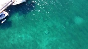 Aerial view of sailboats on the dock or peer and people on vacation. Boat is moored on island Olib in Croatia. Drone shot of tourists enjoying nautical tourism in Adriatic sea, resting on the peer.