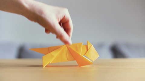 Hand moving a yellow Origami Tiger on table. Symbol for happy Chinese new year. Tiger is the Chinese zodiac sign for 2022. Golden animal made with traditional Japanese paper folding technique. 4K.