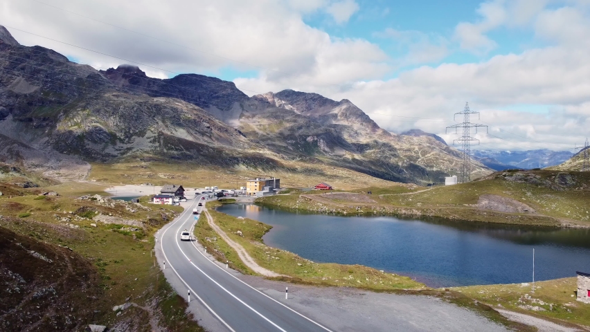 Cars and other vehicles driving along the Bernina pass mountain road in Canton Graubunden in the alps in Switzerland. Drone footage with a following and forward motion