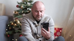Sad man at home feeling lonely during Christmas Eve day make video phone call with friends and parents - concept of people and online internet technology, modern lifestyle
