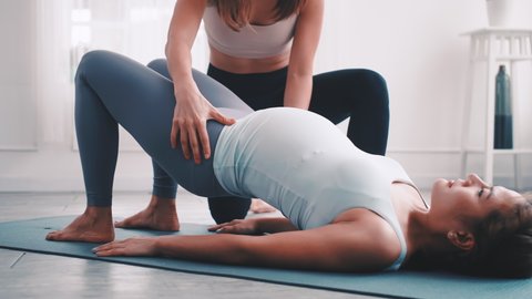 Pregnant woman doing Pilates exercise with personal trainer at home.