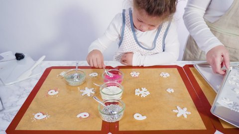 Step by step. Little girl helping to make a homemade lollipops with fondant snowflakes.