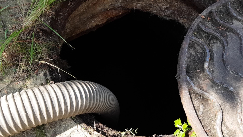 An open manhole. Image of the nodes of the pumping machine for pumping out the septic tank. pumping waste from the sewer. A hose is lowered into the sewer manhole to pump water out of the pit Royalty-Free Stock Footage #1082904379
