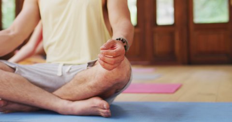 Low section of caucasian man sitting in yoga lotus position during yoga class at studio. fitness, healthy hobbies and active lifestyle. ow