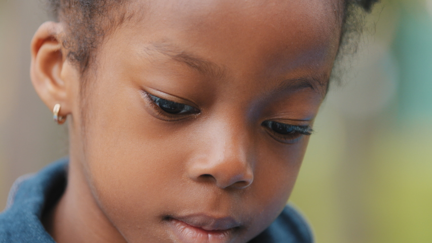 Close-up pensive little girl african american child raises head looking at camera front view sad baby outdoors portrait unsmiling schoolgirl beautiful unemotional face of lonely cute kid bored look Royalty-Free Stock Footage #1082913835