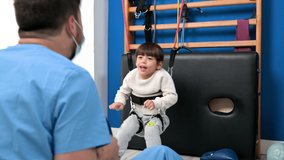Cute kid with cerebral palsy doing musculoskeletal therapy in the hospital while laughing and having fun . High quality 4k footage