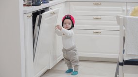 Baby boy wearing soft safety helmet learns to stand, walk. Child falling on the floor, head protector helps reduce impact of fall. High quality 4k footage