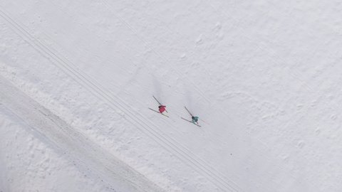 AERIAL, TOP DOWN: Professional skiers train at the training center in Slovenia. Flying above two female athletes training skiing in Slovenian mountains. 