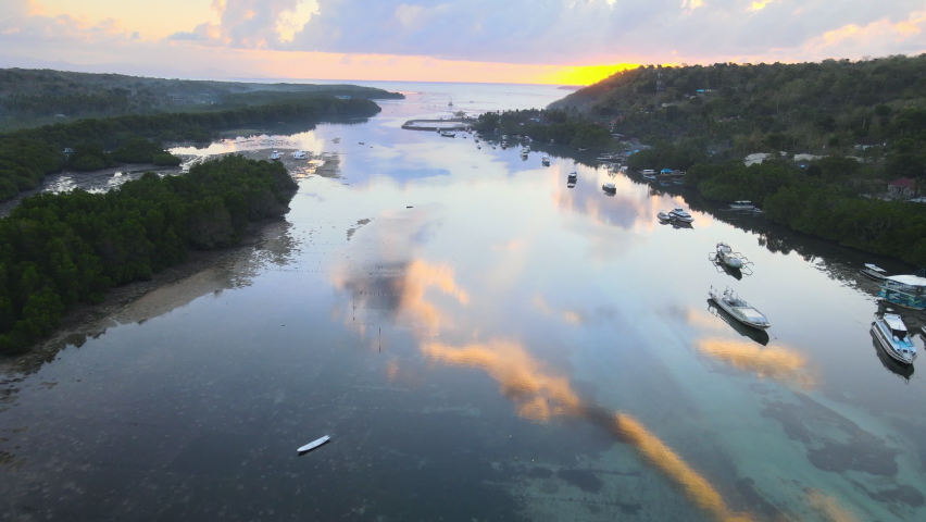 Turquoise water with a calm surface reflects clouds and sky at sunset. The shallow water channel between islands of Ceningan and Lembongan.