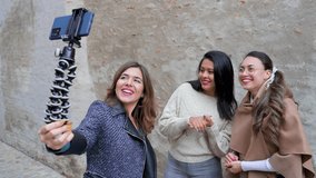 Young attractive females holding a smartphone and talking to camera with smiley excited faces.