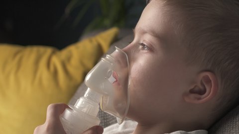 The child does the lung inhalation procedure at home. Inhalation when coughing. Cough treatment in children. Nebulizer inhalation at home