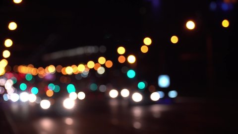 Round colorful bokeh shine from car lights in traffic jam on city street. Beautiful glittering bokeh in dark blurry background at night. Abstract concept. Reflects lonely capital city lifestyle.