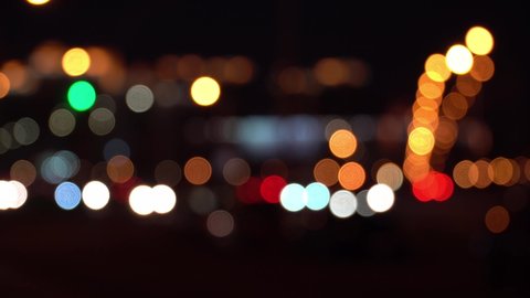 Beautiful glittering bokeh in dark blurry background at night. Round colorful bokeh shine from car lights in traffic jam on city street. Abstract concept. Reflects lonely capital city lifestyle.