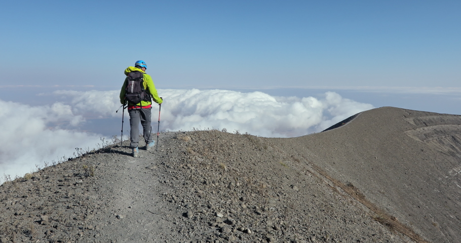 The man conquered the top of the mountain and walks along the ridge. Beautiful landscape with thunderstorms under which there are clouds in Africa.