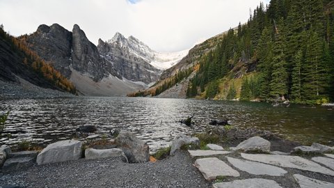 Rocky mountains with water flowing in autumn forest on Lake Agnes Tea House in Banff national park, Alberta, Canada
