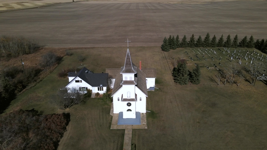 Aerial footage in 4k orbiting an old catholic prairie church in rural Alberta, Canada. While circling St Boniface Church drone gets closer to the single steeple. Remote location captured on sunny day.