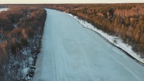 Unusual winter landscape with a frozen river at sunset, aerial view. The ground is covered with white snow. Video, footage, splash screen, intro, presentation, copy space. UHD 4K.