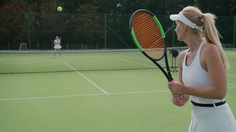 Back view of female tennis player hits the ball with a racket, female hits off the opponent's serves during tennis match, active game, 4k 50fps.