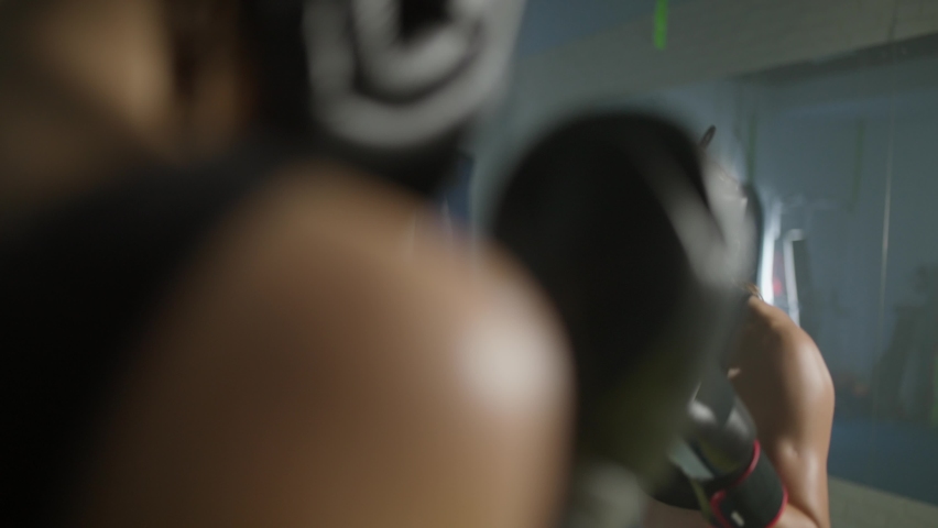 Sparring fight of two woman fighters wearing protective helmets, training in the boxing gym, females train defence and series of punches on a battle.