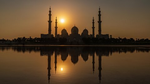 Sheikh Zayed Grand Mosque in Abu Dhabi in UAE- Time Lapse of day to night transition seen from Wahat Al Karama with the mosque reflected in pond