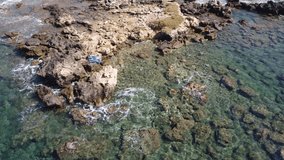 Aerial video view from drone on underwater reefs and coastal rocks in mediterranean sea near beaches with clear transparent water. Camera looks down. Crete, Greece.