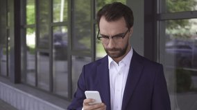 Businessman in suit using mobile phone outdoors