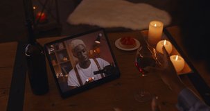 Online dating at home. African american couple chatting and drinking wine during video conference on digital tablet. Young woman sitting at room in romantic atmosphere.