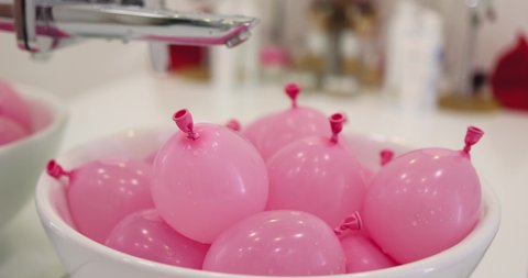 a bunch of pink water balloons in a sink. ready for the kid's water fight. leisure activity