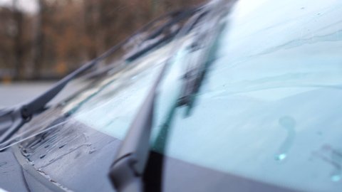 The side view of the windshield of car with working windshield wipers.