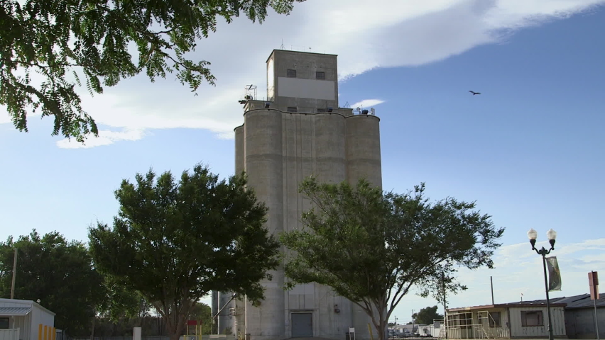An old industrial building exterior with trees in the foreground.  General b-roll of Garden City Kansas on a sunny day establishing shot showing rural, small town life in America.