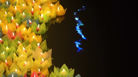 Floating colored lanterns and garlands on river at night on Vesak day in Saigon River for celebrating Buddha's birthday, that made from paper and candle. Commemorating those who have passed away