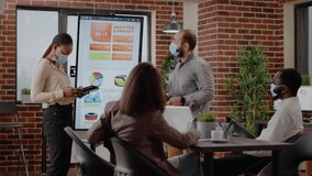 Business people explaining financial project and presentation to colleagues in boardroom. Workmates presenting data charts analysis on monitor at meeting during coronavirus pandemic. - Powered by Shutterstock - Get 15% off with code: PIKWIZARD15