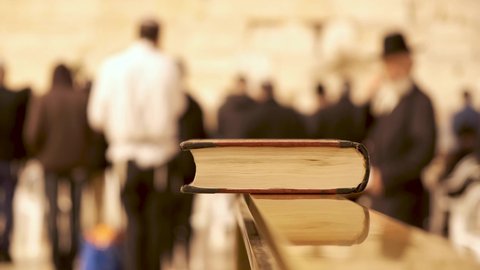 Close up of book in the western wall Jerusalem. Religious jews praying in the background at the wailing wall. A Torah book at the Kotel Israel