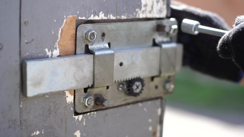 Repairing old door lock in rural barn or garage. Replacing broken part with new one