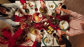 Friends holding hands and praying before dinner top view, new year tradition, sitting at dining table. International young people eating delicious food during christmas party at home.  - Powered by Shutterstock - Get 15% off with code: PIKWIZARD15