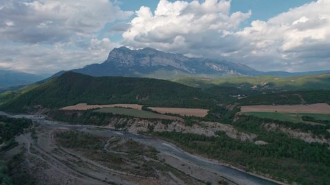 A great mountain, a rock protruding on a plateau in the Pyrenees mountains. Spectacular view of the mountain range from a drone with huge cumulus clouds in the background.