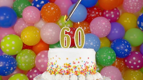 Cake with burning candles number 60. Celebration cake on a bright festive background of colorful balloons.