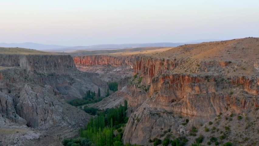 Zoom out view scenic ihlara valley rock cliffs with beautiful textures on sunset with green tree valley