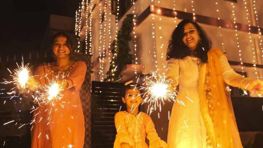 Shot of a beautiful Girls Celebrating Diwali Festival in India. An Indian family playing with fire crackers and looking into camera with beautiful smile. A festival of light in India. Royalty-Free Stock Footage #1083002764