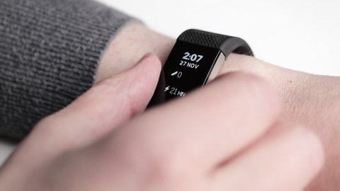 London UK  - 27th November 2021 - A woman taps through settings on her Fitbit watch, macro closeup. 