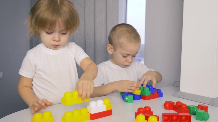 Happy children at home at the table build a house of colored cubes. P Royalty-Free Stock Footage #1083006415