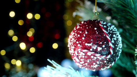 A shiny decorative ball decorated by hand rotates. Bright lights of garland bulbs in the background. The concept of creating christmas decor. High quality. 4k footage.
