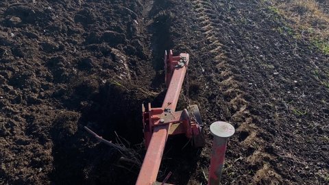 Top view of simple plow attached to tractor plowing the field  