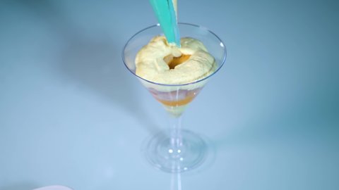 Cream is placed over ladyfingers in the plastic chalice