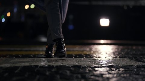 woman is walking in city in evening, details shot of legs in dark street, autumn and rainy weather