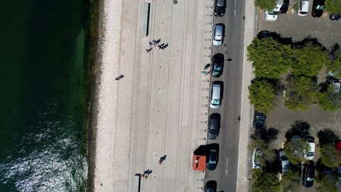 Aerial view above people on the coastal promenade of Belem, in sunny Lisbon, Portugal - top down, drone shot