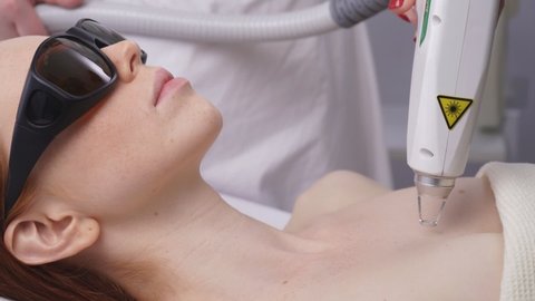 Cosmetologist performs fractional laser skin treatment to restore and rejuvenate the female skin of the face and decollete.